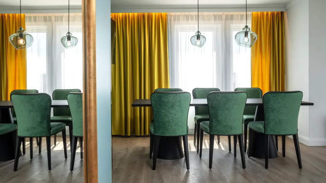 Spisebord, 6 grønne stoler, vindu, gule gardiner, parkettgulv