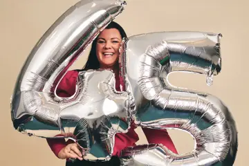 Elisabeth som holder folieballonger med nummerene nr "4" og "5"