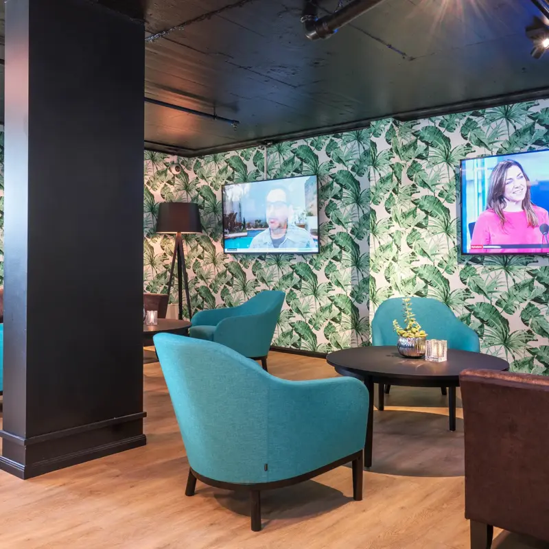 Fire blå lenestoler og to sorte sofaer i lobbyen på Thon Hotel Linne