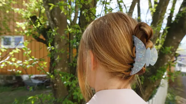 Nærbilde av kvinne med håret satt opp av hårklype, sett bakfra