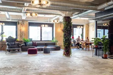 Interiør fra kontoret til The Oslo Company, stor og åpen sosial sone med rustikke detaljer som betonggulv og ventilasjon, grønne planter og lyse farger på veggene