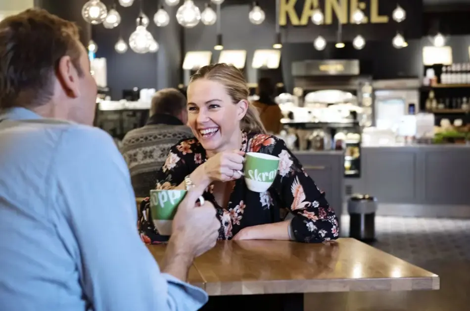 to personer med skravlekopper sitter og prater på kafè