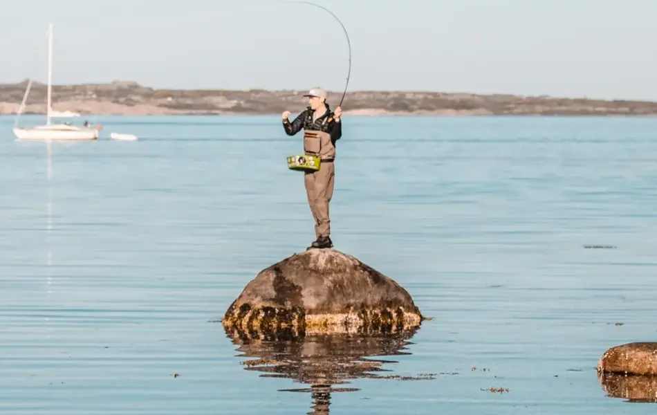 Mann står på en liten holme og fisker