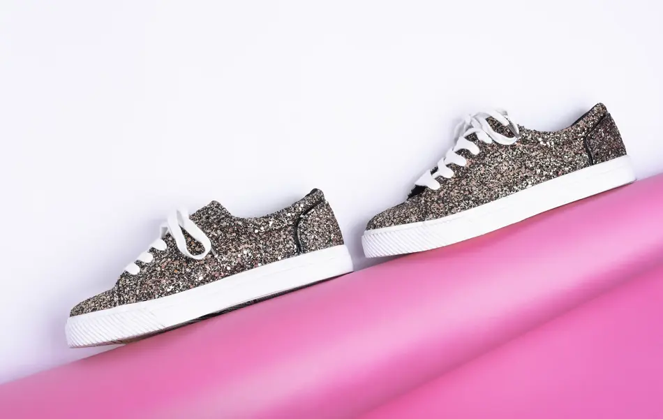 Glitrende sneakers mot en hvit og rosa bakgrunn