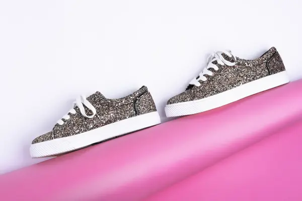 Glitrende sneakers mot en hvit og rosa bakgrunn