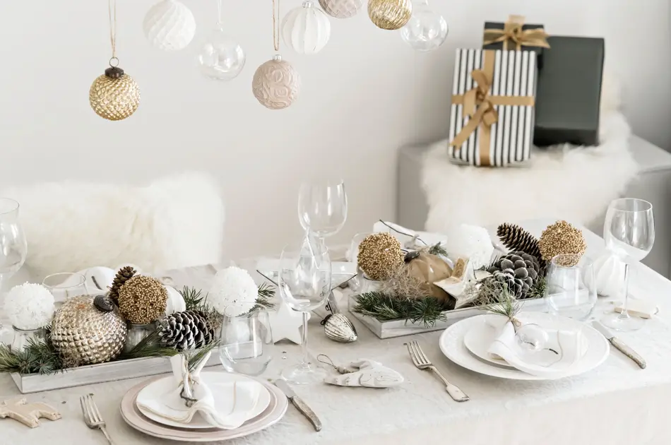 Julebord pyntet med hvitt, sølv og bronsje med detaljer som julekuler, kongler og julegaver