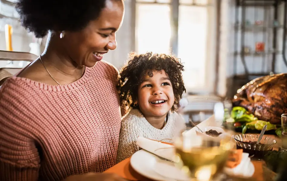 dame som sitter med sønnen sin på fanget foran middagsbordet
