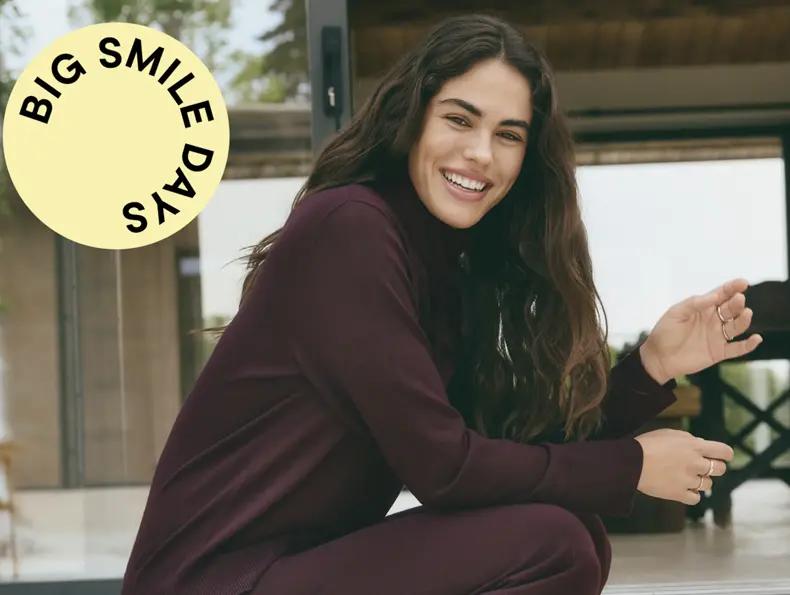 En kvinna i ett matchande set för hemmabruk sitter utomhus på en terrass.