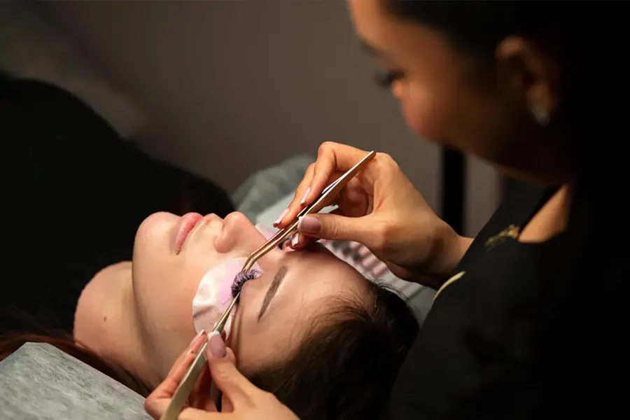 dame som setter på løsvipper på en annen dame