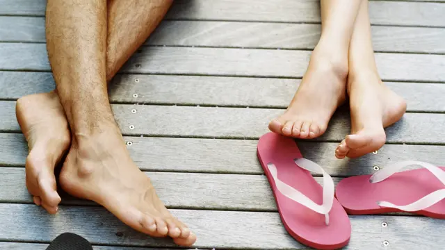 Nærbilde av to par ben på brygge med flip flops 