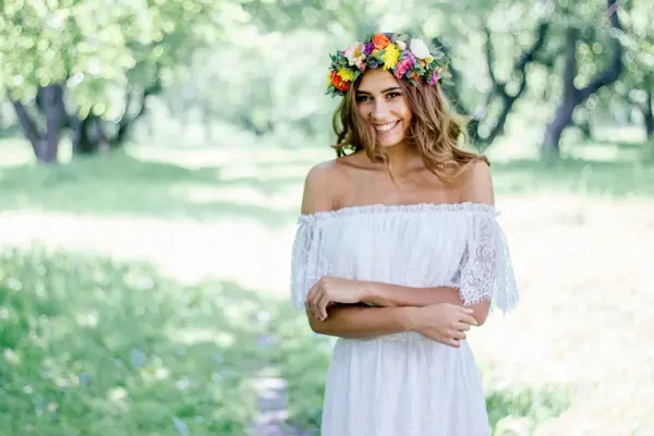 kvinne ute i hvit blondekjole og blomsterkrans