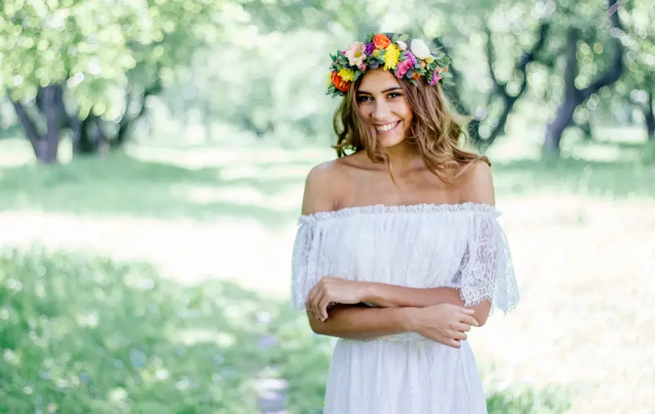 kvinne ute i hvit blondekjole og blomsterkrans