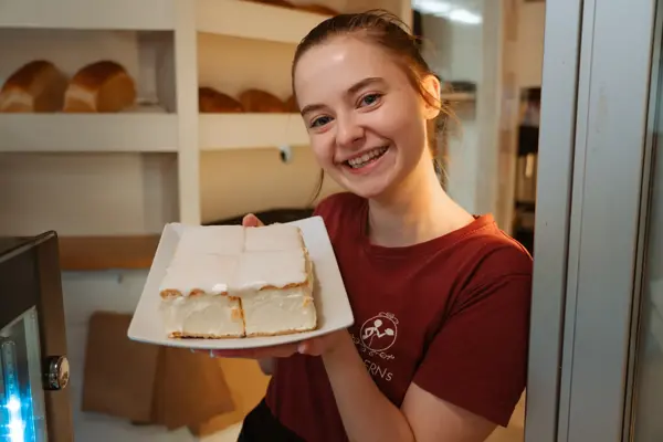 ansatt hos Moderns Café viser frem fat med napoleonskake