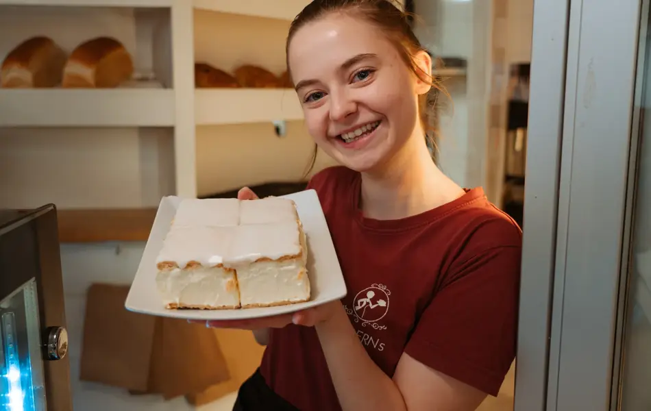 ansatt hos Moderns Café viser frem fat med napoleonskake