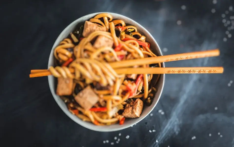 Asiatiske nudler i tallerken med spisepinner