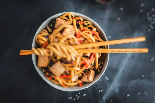 Asiatiske nudler i tallerken med spisepinner
