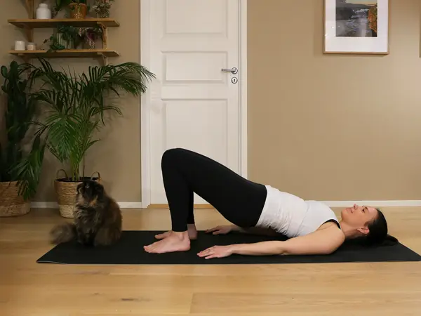 Anna viser Pilates-øvelser på treningsmatte på gulvet
