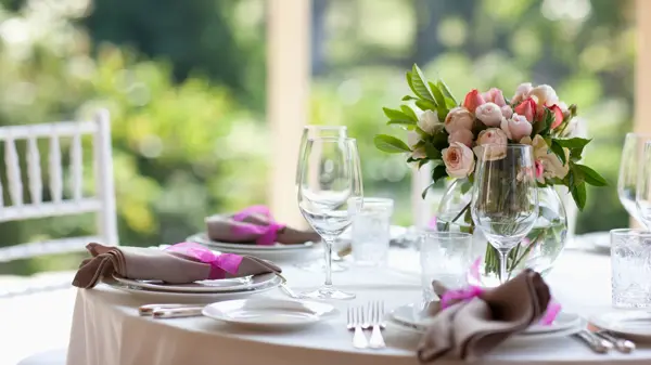 Bukett med peoner på et dekket, rundt bord