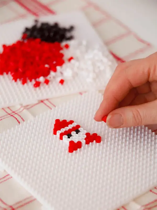 Nærbilde av hånd som perler en nisse. Foto til artikkel om julepynt du kan lage selv.