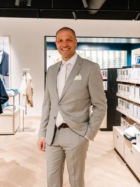 mann i dress står i butikk