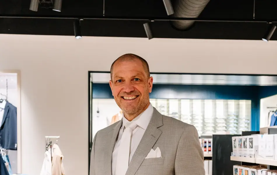 mann i dress står i butikk