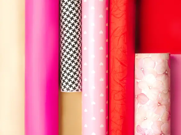 Holidays Multi-Colored Wrapping Paper Rolls. Valentine's Day, Love, Birthday themed rolls of red, pink, gold,  black and white color wrapping paper lined up. Close up. Copy space.