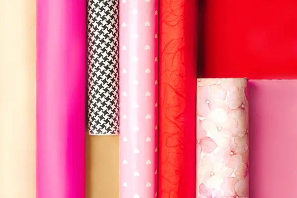 Holidays Multi-Colored Wrapping Paper Rolls. Valentine's Day, Love, Birthday themed rolls of red, pink, gold,  black and white color wrapping paper lined up. Close up. Copy space.