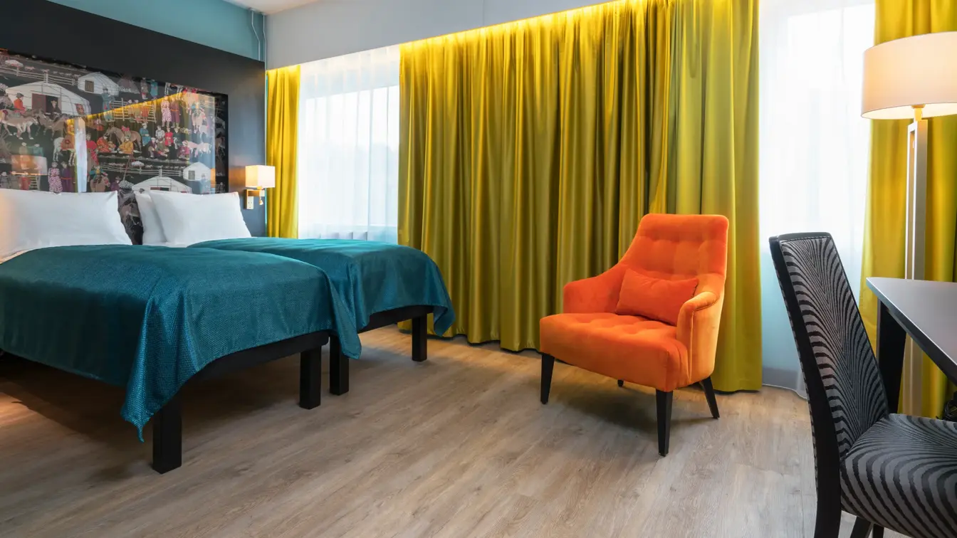 2 senger, en orange lenestol og skrivebord på Thon Hotel Linne