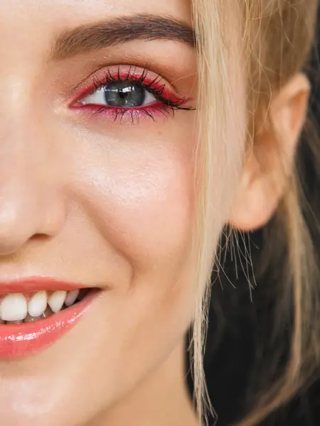 Close up on half face of a gorgeous smile of a beautiful happy blonde woman. Her lips are painted with bright red lipstick, skin is soft and natural and do not miss her stunning white teeth.
