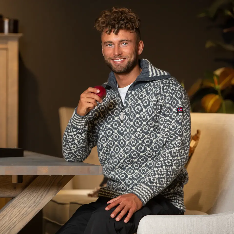 Smilende mann i strikkegenser holder eple