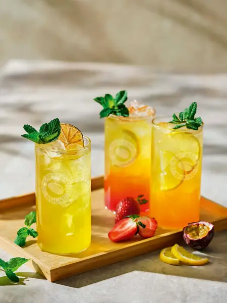 Tre høye glass med limonade på et brett.