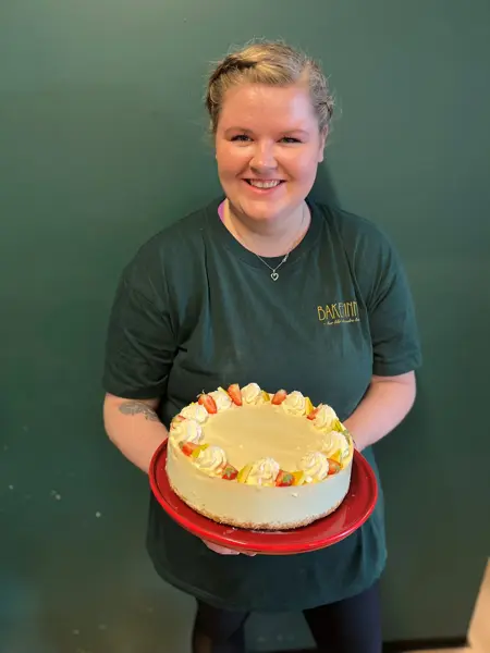 En dame holder en stor, hvit kake