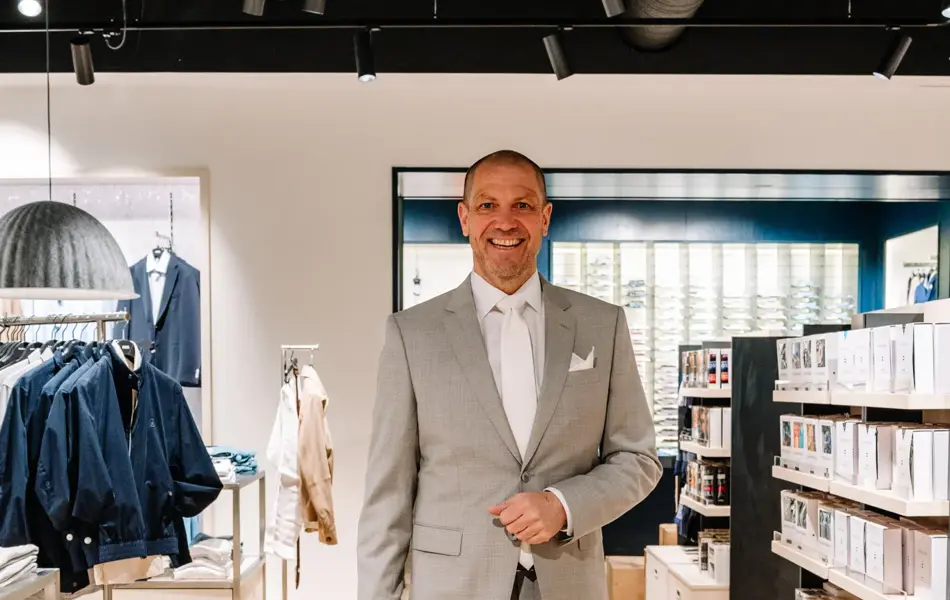 mann i dress står i butikk