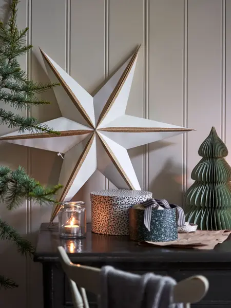 julestjerne, lyslykt, fine pakkeesker og papirtre på et bord