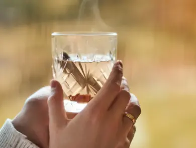 Hånd som holder et glass med varm drikke 