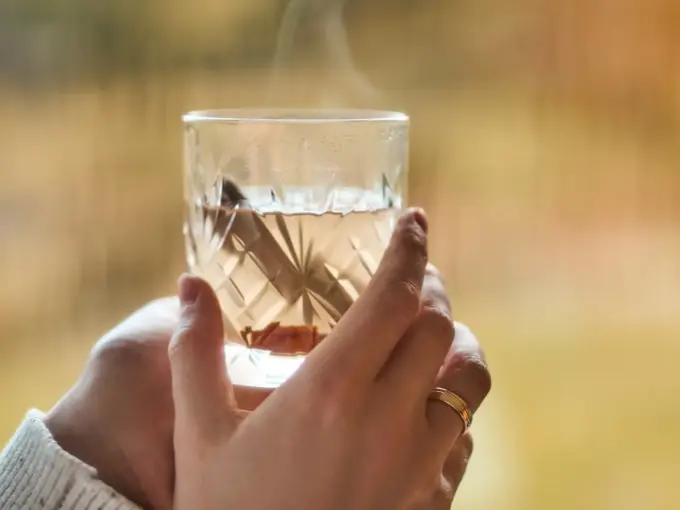 Hånd som holder et glass med varm drikke 