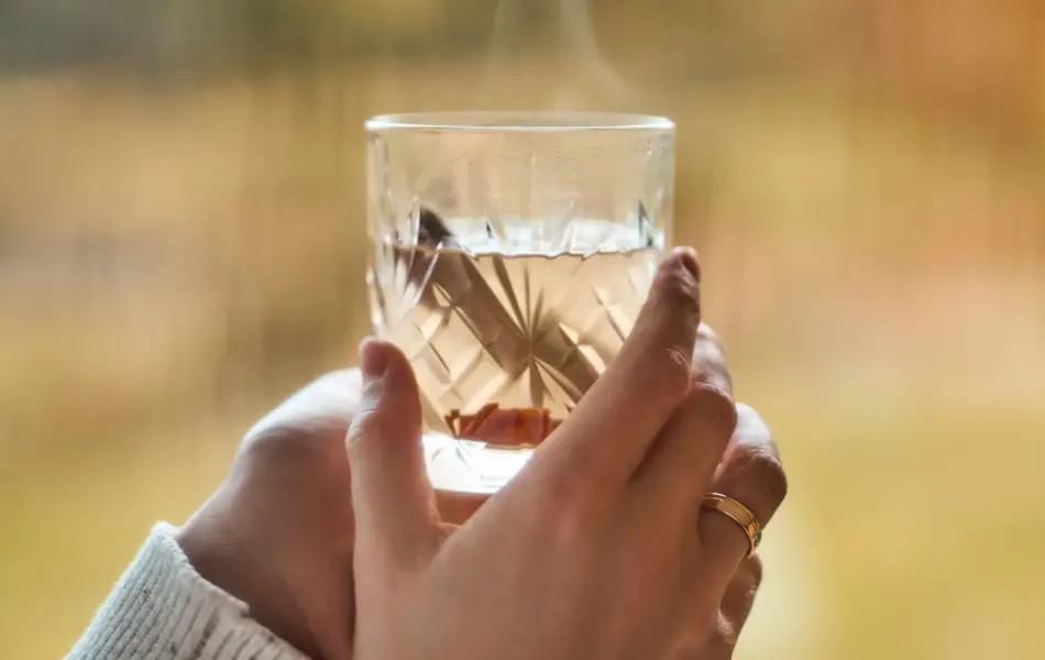 Hånd som holder et glass med varm drikke 