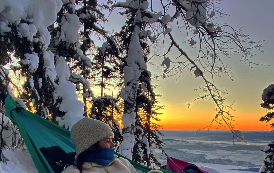 Pia Husøy som sover i hengekøye på vinteren med solnedgang i bakgrunn