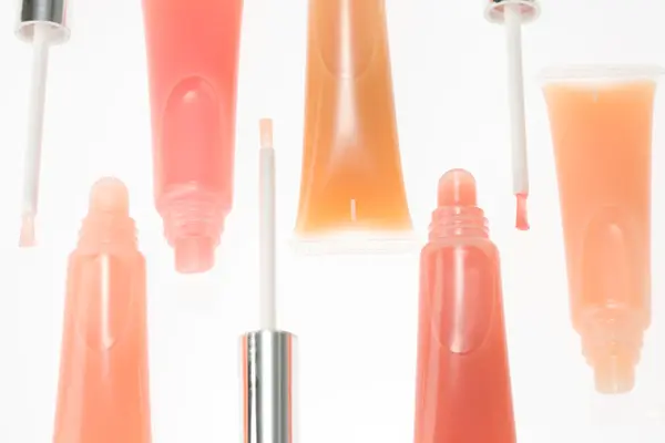 Nærbilde av lipglosstuber i oransjetoner