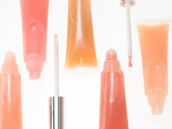 Nærbilde av lipglosstuber i oransjetoner