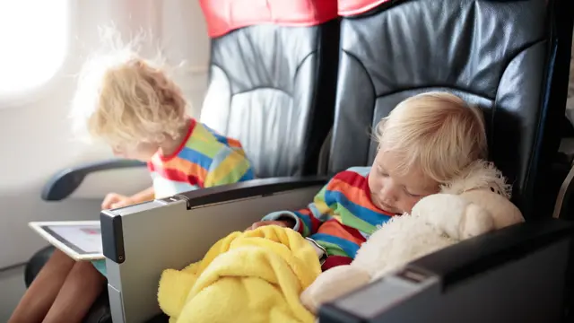 Child in airplane. Kid in air plane sitting in window seat. Flight entertainment for kids. Traveling with young children. Kids fly and travel. Family summer vacation. Little boy with toy in airplane.