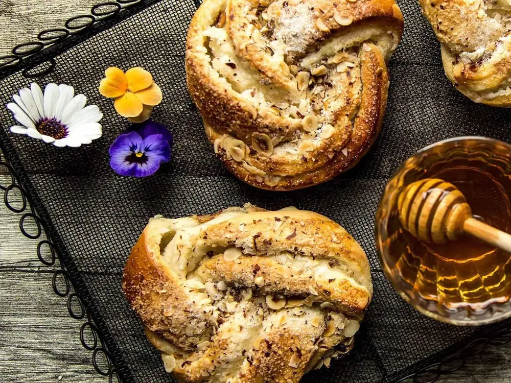 Bakevarer dekorert med blomster og et skål med honning