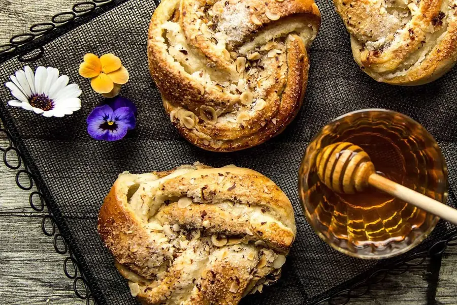 Bakevarer dekorert med blomster og et skål med honning