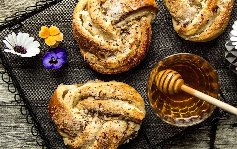 Bakevarer dekorert med blomster og et skål med honning