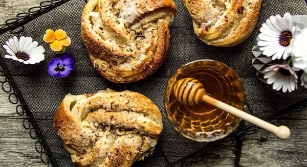 Bakevarer dekorert med blomster og et skål med honning