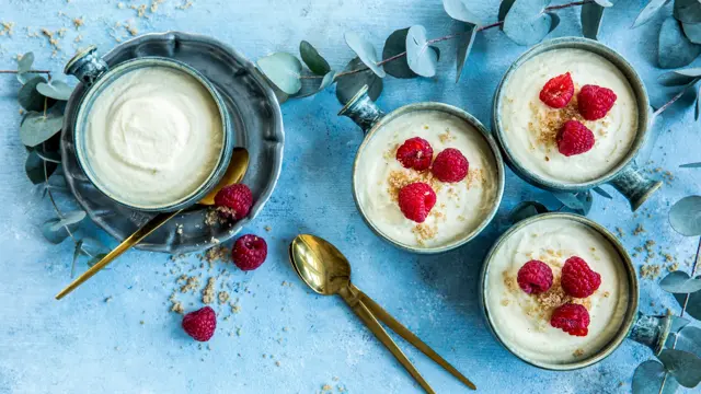 Fire skåler med hvit sjokolademousse dandért med friske bringebær og revet sjokolade