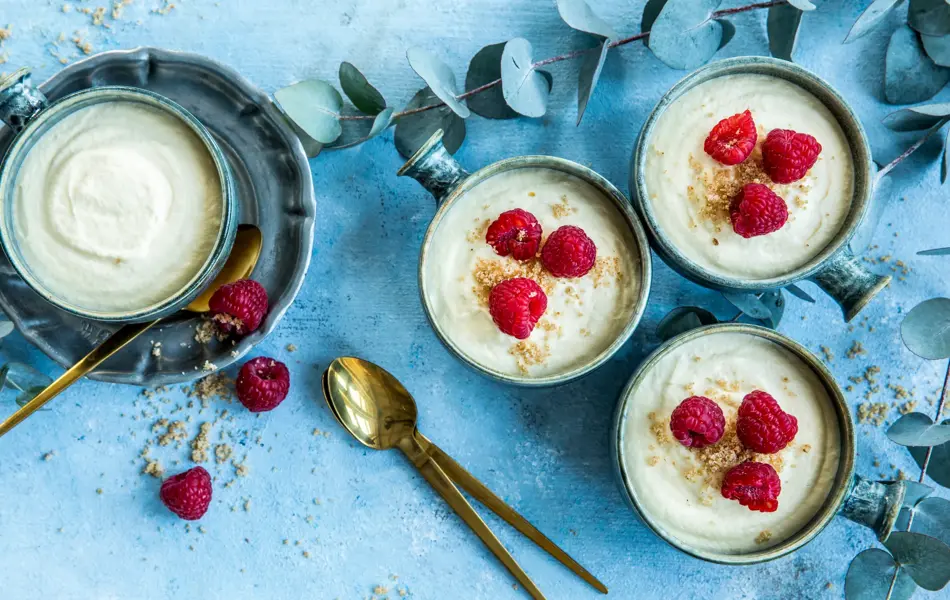 Fire skåler med hvit sjokolademousse dandért med friske bringebær og revet sjokolade