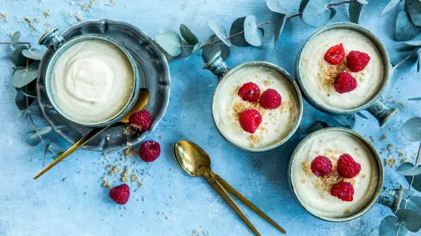 Fire skåler med hvit sjokolademousse dandért med friske bringebær og revet sjokolade