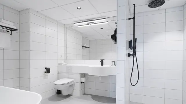 Flislagt bad med dusj, servant, stort speil og toalett.