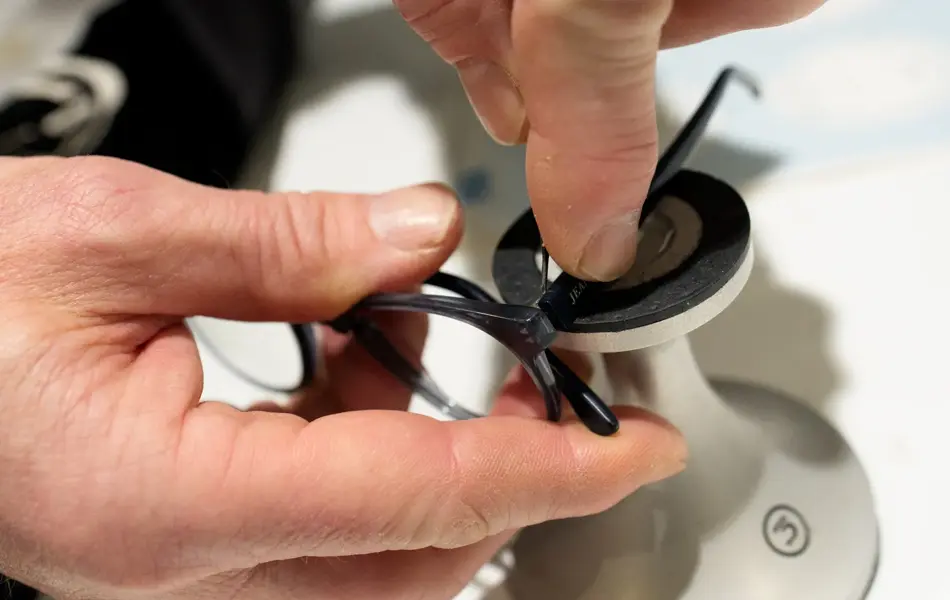 Nærbilde av hender som reparerer en brilleinnfatning